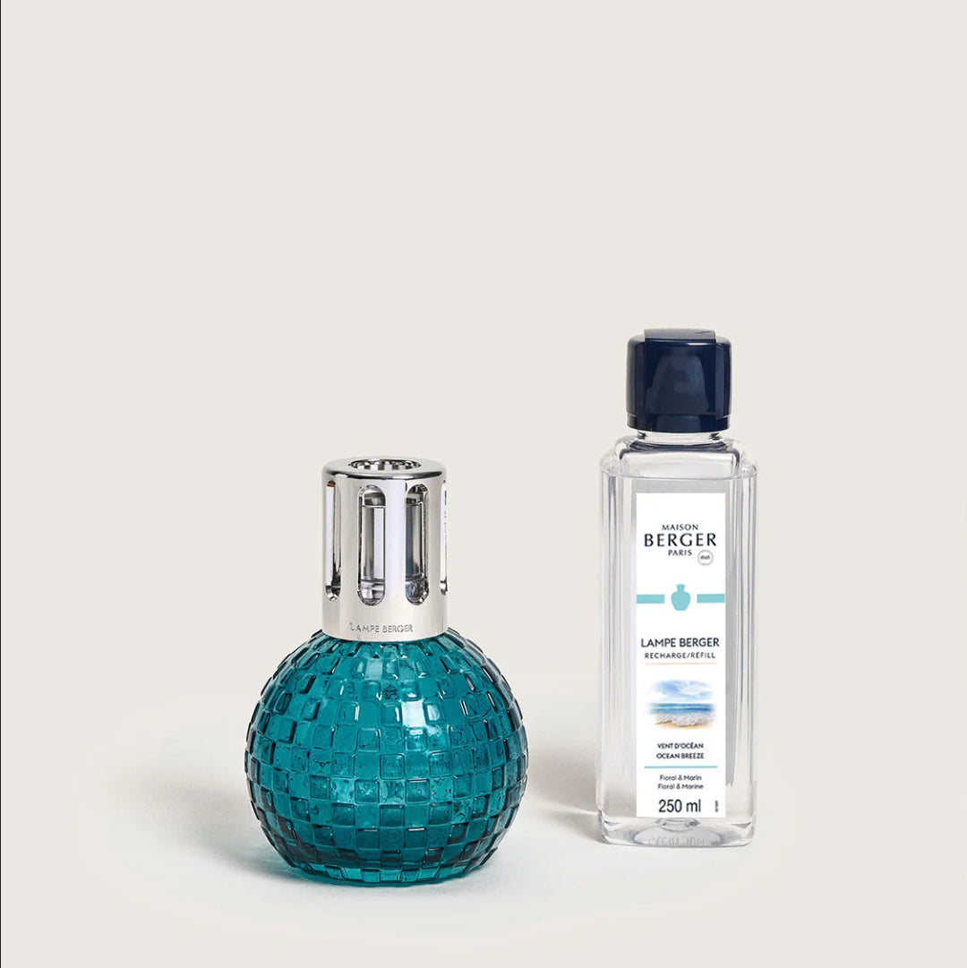 A teal textured glass lamp next to a bottle of Ocean Breeze fragrance refill.
