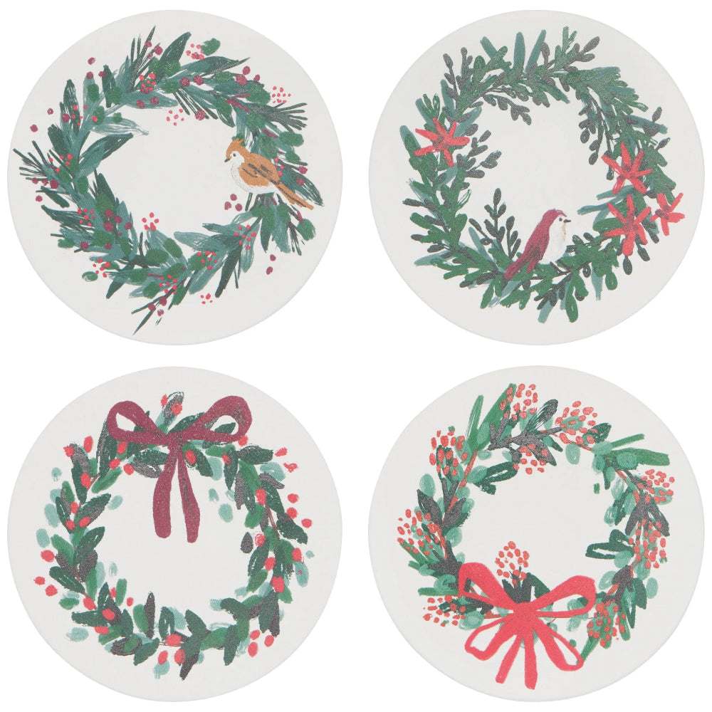 Four round coasters with Christmas wreath designs on a white background