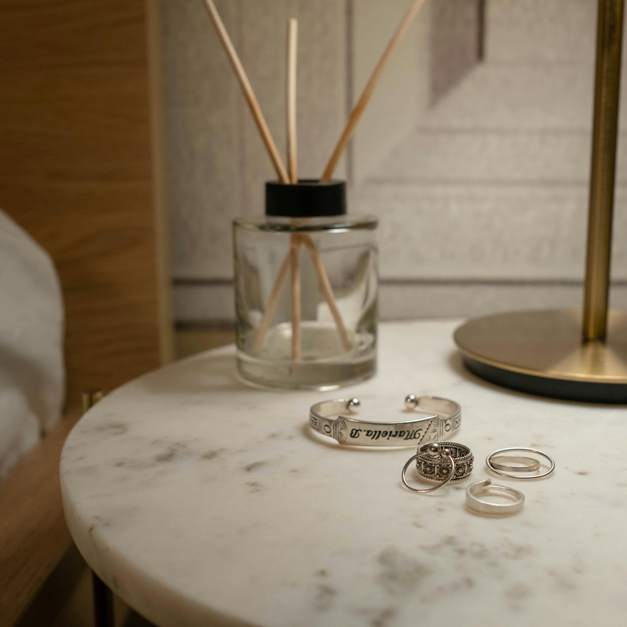 Jewelry on a marble surface with a diffuser in the background