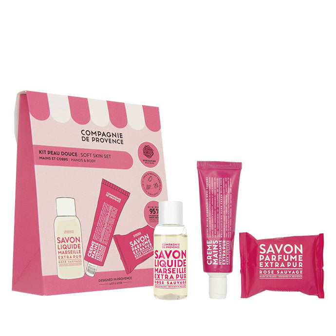 A gift set by Compagnie de Provence including a liquid soap, a moisturizing hand cream, and a perfumed soap, all with a rose fragrance, packaged in a pink box.