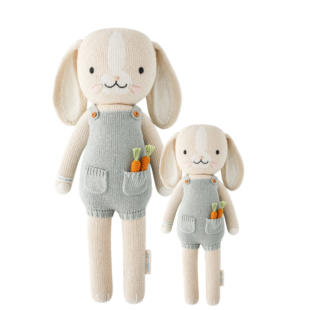 Two sizes of a hand-knit beige bunny doll with overalls and carrots, made from premium cotton yarn.